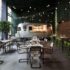 an outdoor dining area with tables, chairs and a food truck in the back ground