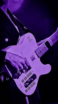 a man is playing an electric guitar in purple and black color scheme with his hand on the neck