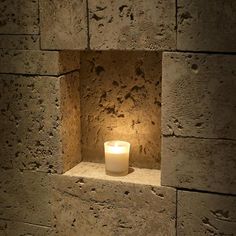 a lit candle sitting in a stone niche