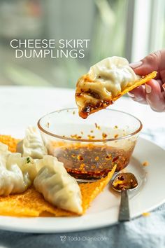 a person dipping sauce onto dumplings on a plate