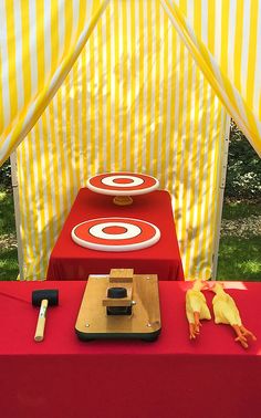 a red table topped with two plates and a knife next to a yellow striped tent