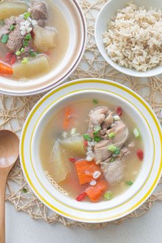 two bowls filled with meat and vegetables next to rice on a place mat near a wooden spoon