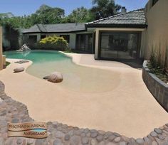 a house with a pool in the front yard and landscaping around it, including rocks