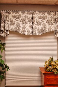 a window with a flower arrangement on top of it next to a dresser and potted plant