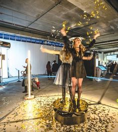 two women standing on top of a table with confetti in front of them