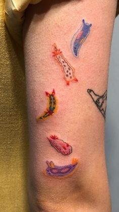 a woman's arm with tattoos on it and various things painted on the arm