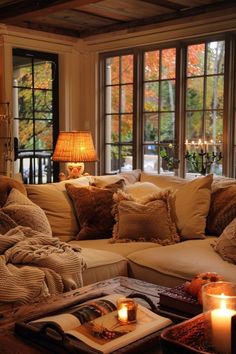 a living room filled with lots of furniture next to a window covered in fall leaves