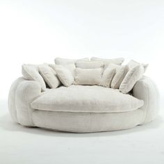 a white couch with pillows on it in front of a white wall and flooring