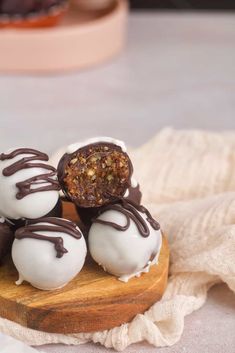 four chocolate covered donuts sitting on top of a wooden board