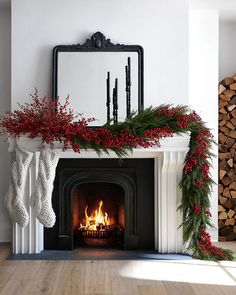 a fireplace decorated for christmas with red berries and greenery