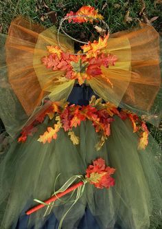 a dress made out of tulle with flowers and leaves on the bottom, sitting in grass