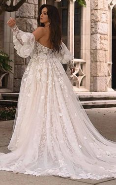 a woman in a wedding dress is standing on the sidewalk and looking off into the distance