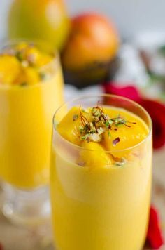 two glasses filled with orange juice and garnished with pistachios on the rim