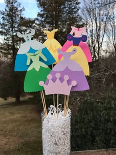 some paper cut outs are in a vase with toothpicks on the table outside