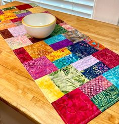 a bowl is sitting on top of a colorful table runner made out of patchwork fabric