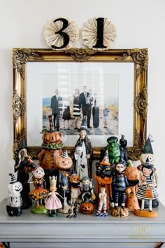 a group of halloween figurines sitting on top of a table next to a framed photo