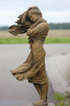 a statue of a woman with her hair blowing in the wind on a cement block