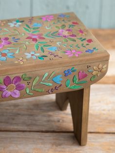 a small wooden stool with painted flowers on it