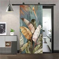 an open door that has a painting on it with tropical plants and leaves in the background