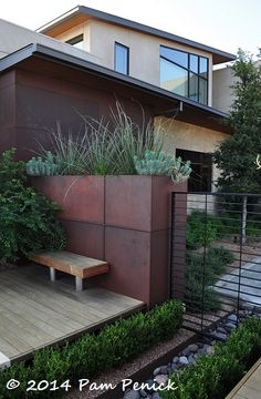 a wooden bench sitting in front of a tall building with plants growing on it's sides