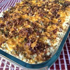 a casserole dish with cheese and meat in it on a red tablecloth