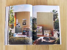 an open book with pictures on it sitting on top of a wooden table next to a plant