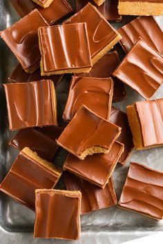 there are many pieces of chocolate and peanut butter bars on the tray together, ready to be eaten