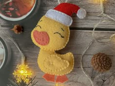 a stuffed ducky with a santa hat on sitting next to some pine cones and christmas lights