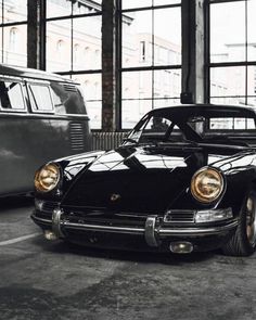 an old black car is parked in a parking lot next to two other cars and windows