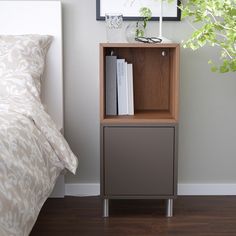 a book shelf next to a bed with a plant on top and books in it