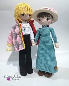 two crocheted dolls standing next to each other on a white surface with one holding the hand of another doll