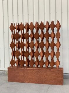 a wooden sculpture sitting on top of a cement floor next to a white wall and door