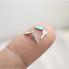 two tiny keys are on top of each other in the palm of someone's finger