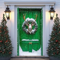 a green door decorated with christmas wreaths and deer's head in the snow