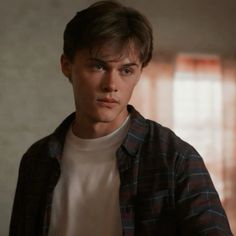 a young man in a plaid shirt looking at the camera with an intense look on his face