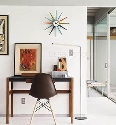 a desk with a chair, lamp and pictures on the wall