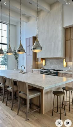 a large kitchen island with stools and lights hanging from it's ceiling over the counter