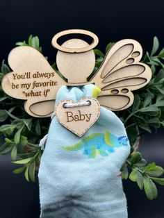 a wooden angel ornament sitting on top of a blue cloth bag next to green leaves