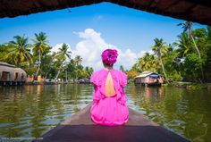 a woman sitting on the end of a boat looking out at some water and palm trees