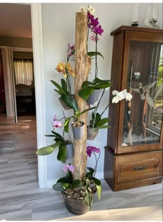 there is a tall planter with flowers in it on the floor next to a cabinet