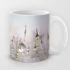 a coffee mug with water droplets on the surface and grass in the foreground, against a white background