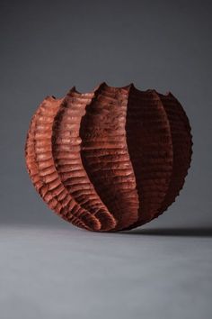 a brown vase sitting on top of a gray table next to a black wall and floor