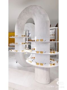 a large white sculpture with gold circles on it's sides and shelves in the background