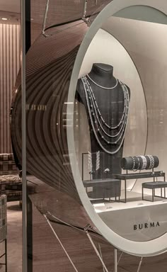 a display case with necklaces in it and a mirror reflecting the mannequin's torso