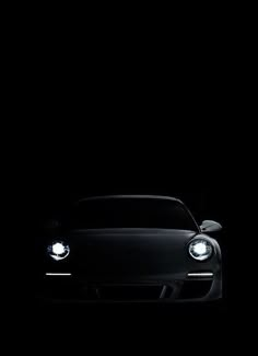 a black sports car in the dark with its headlights turned on and headlamps lit up