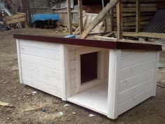 a dog house built into the side of a fenced in area with debris around it