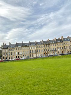 a group of buildings sitting next to each other on a lush green field in front of a blue cloudy sky