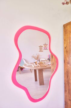 a mirror that is on the wall in front of a table with chairs and a vase