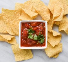 tortilla chips and salsa in a white bowl with garnish on the side