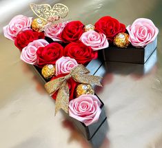 a heart shaped box filled with red and pink roses on top of a silver table